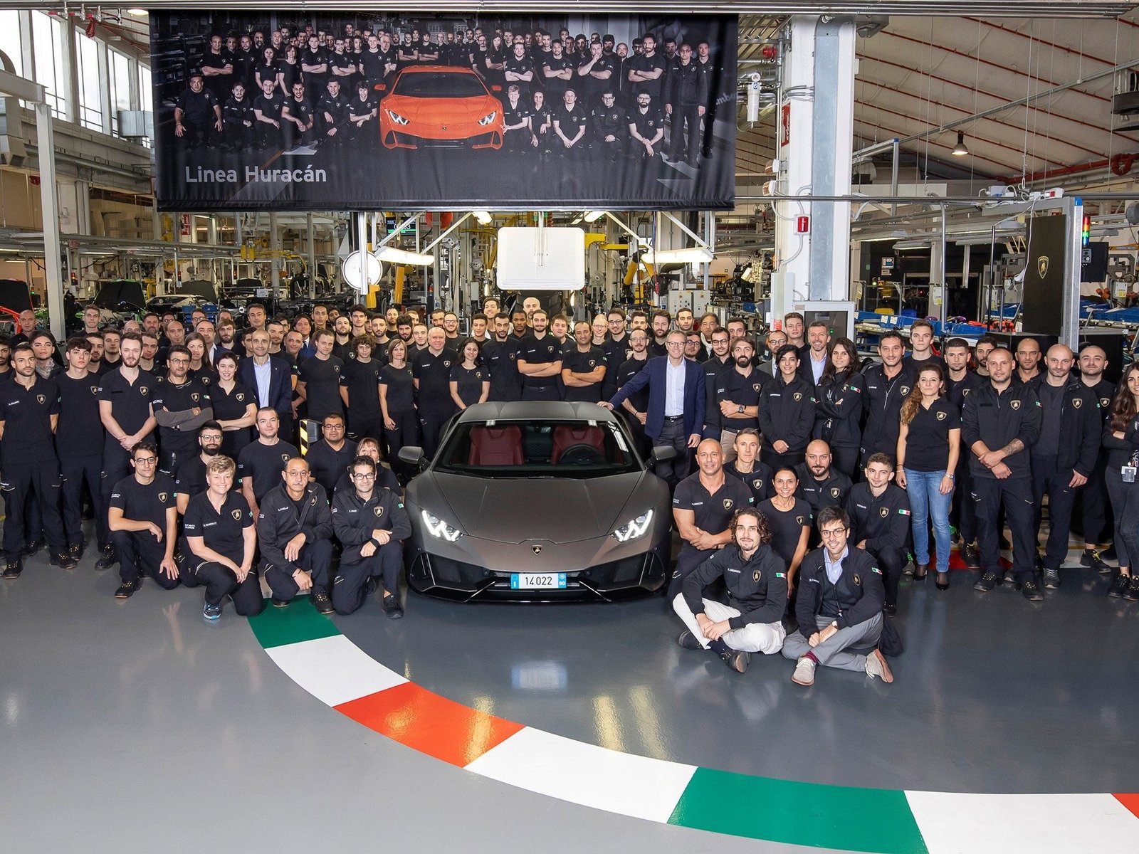 Lamborghini factory workers and executives celebrate around the 14,022nd Huracán EVO on the production line beneath the Linea Huracán banner