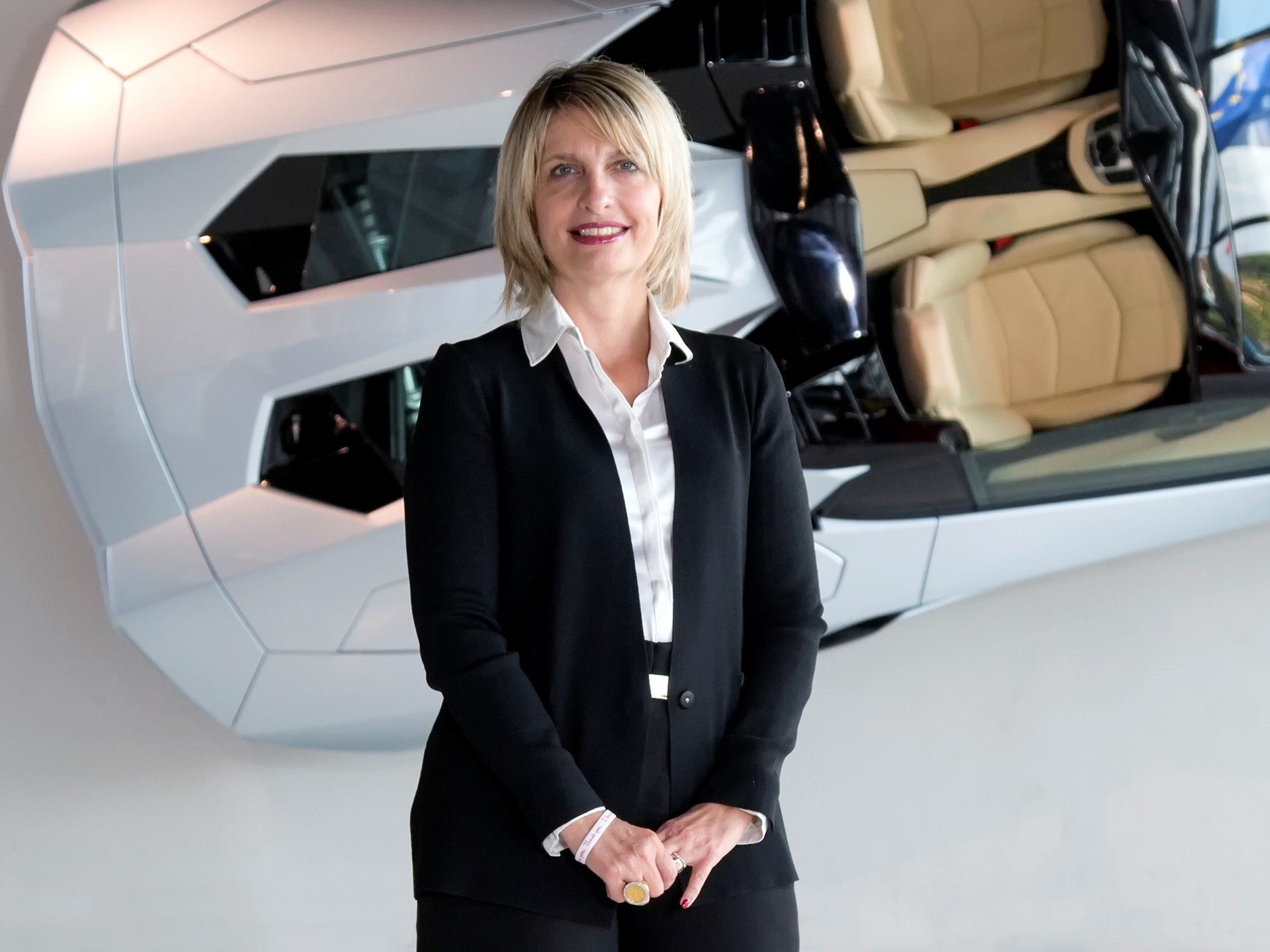 Katia Bassi standing in front of a white Lamborghini Aventador chassis at Sant'Agata Bolognese