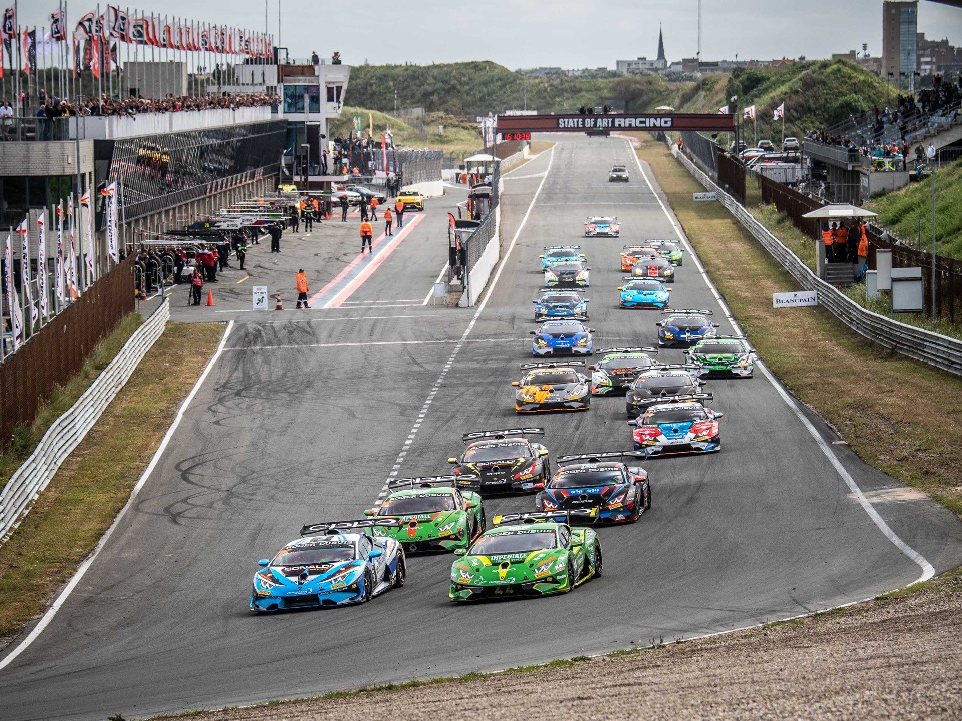 Fleet of Lamborghini Huracán Super Trofeo race cars on track at Zandvoort under overcast skies