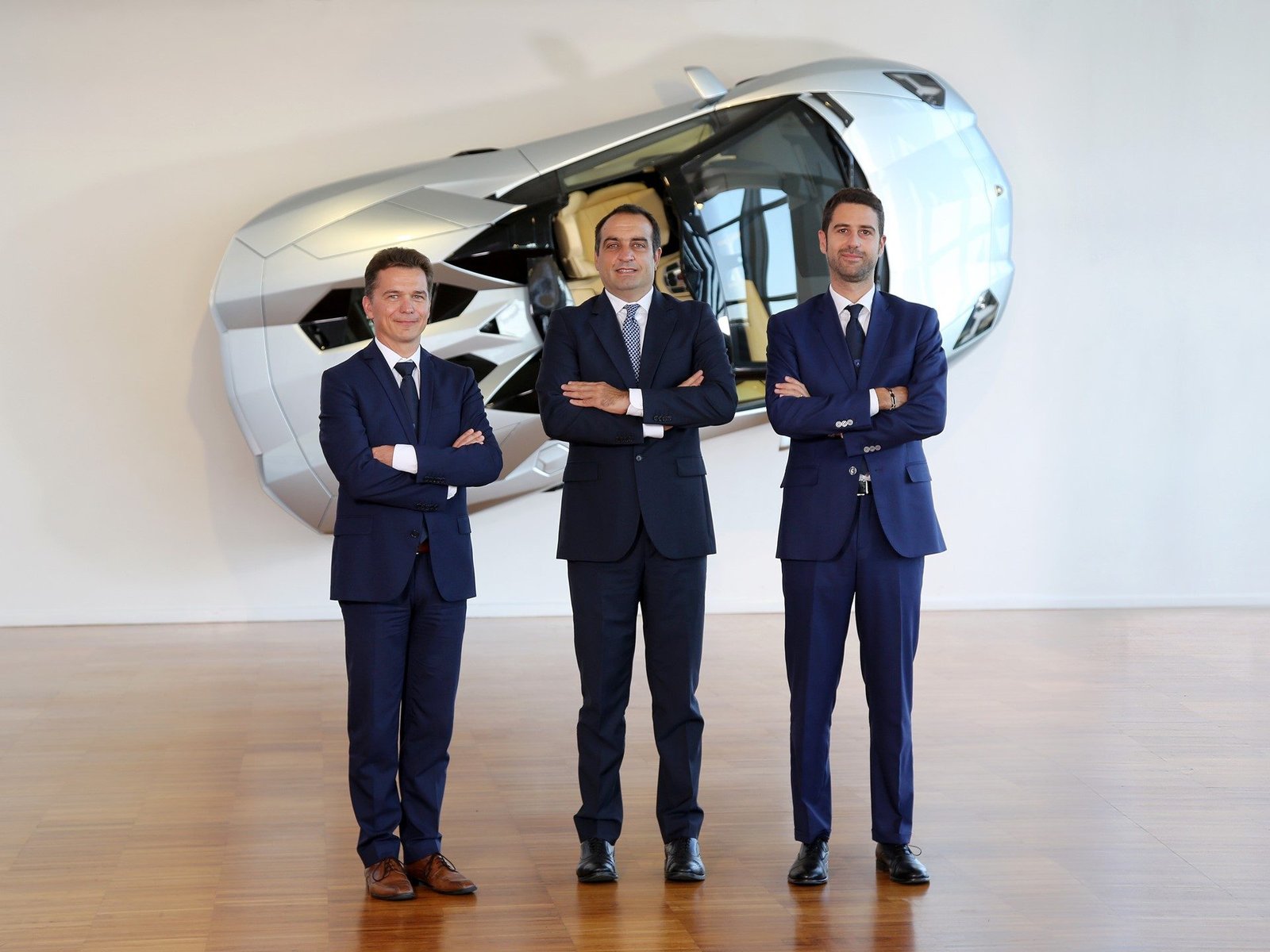 Lamborghini executives in formal attire standing in front of the Terzo Millennio concept car