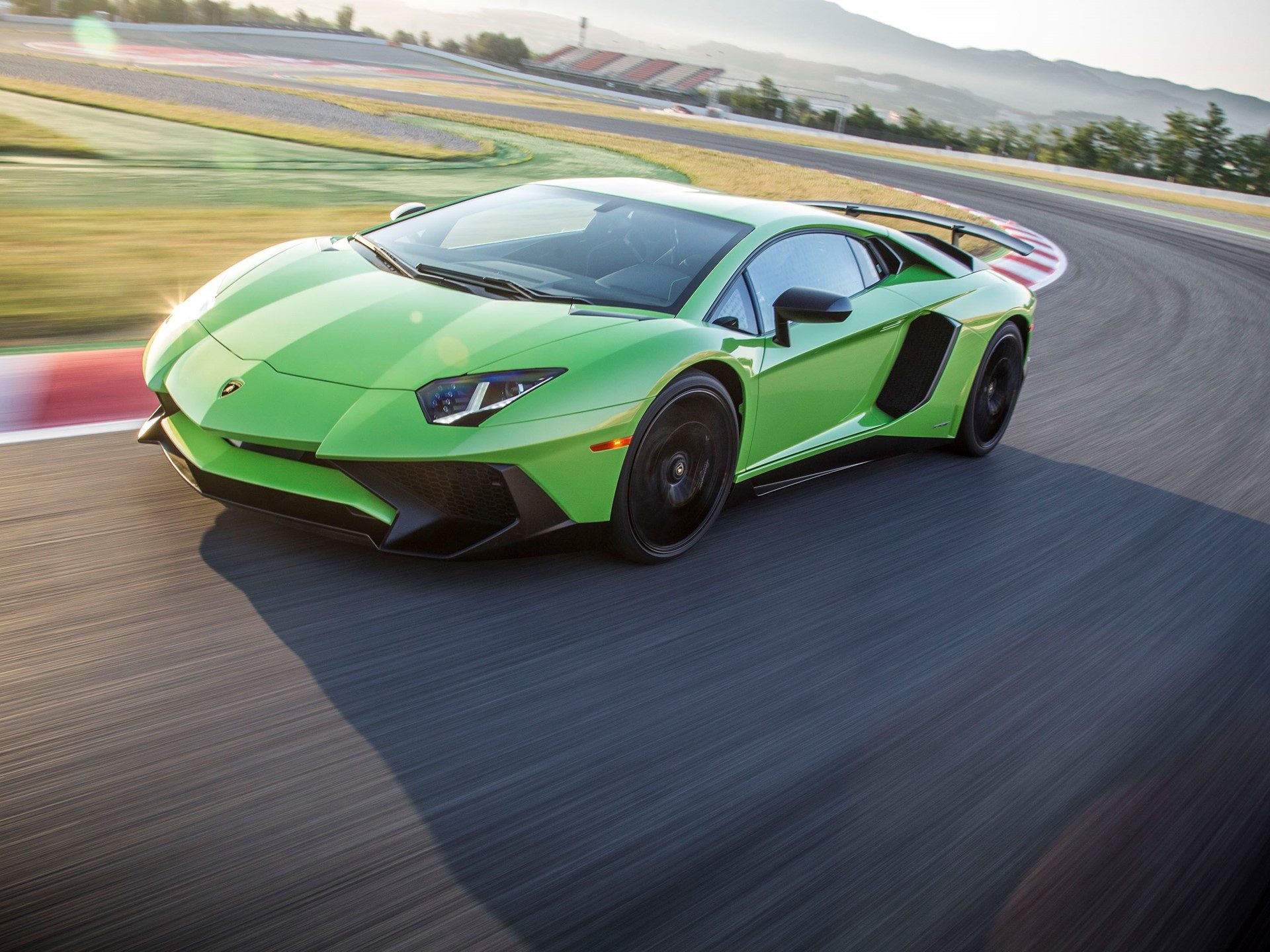 Green Lamborghini Aventador SV cornering hard on a racetrack, showcasing its large rear wing and aggressive aerodynamic design