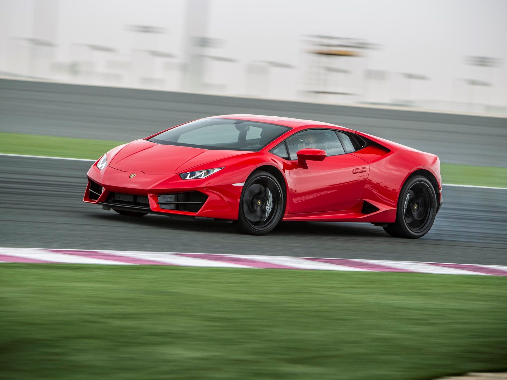 Red Lamborghini Huracán LP 610-4 at speed on a racetrack with motion blur emphasizing velocity