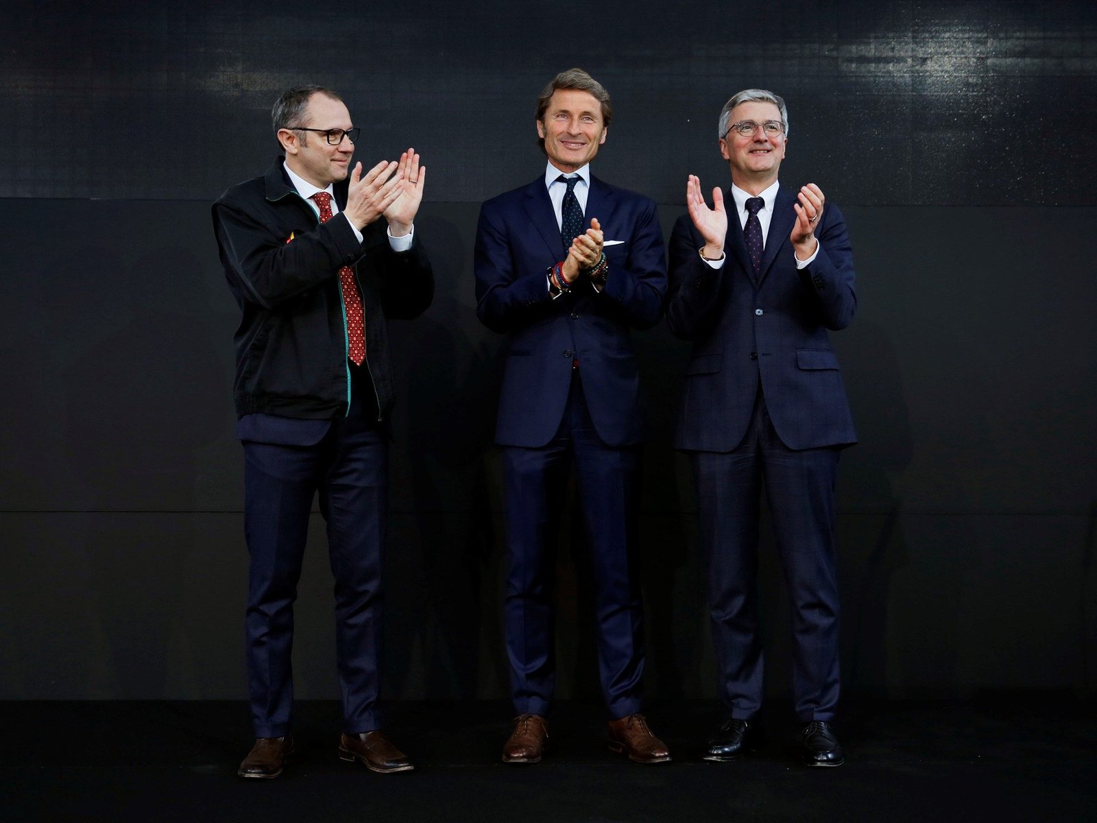 Stephan Winkelmann, Stefano Domenicali, and Rupert Stadler applauding on stage during the 2016 Lamborghini leadership transition ceremony at Sant'Agata Bolognese