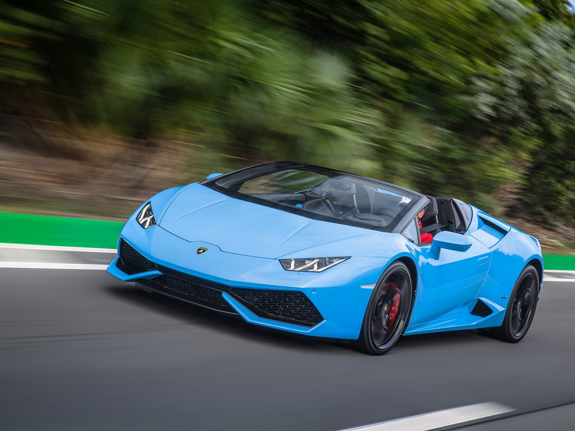 Blue Lamborghini Huracán Spyder at speed, with visible red brake calipers and aggressive front air intakes