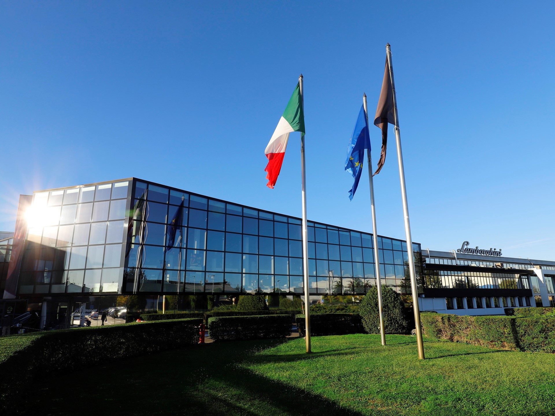 Lamborghini headquarters building in Sant'Agata Bolognese with glass museum facade and Italian flag