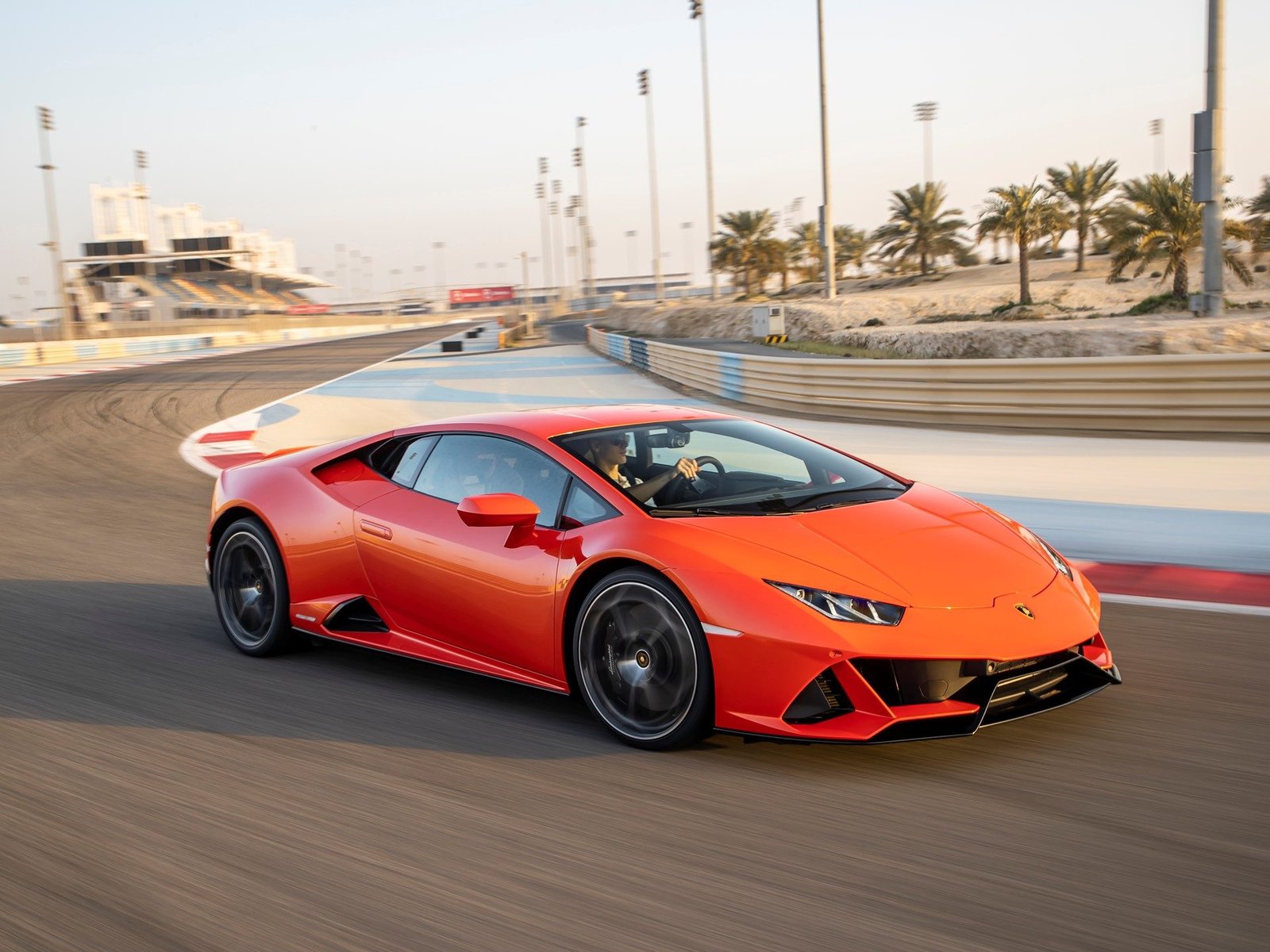 Orange Lamborghini Huracán EVO cornering hard on a racetrack with visible brake calipers and motion blur on wheels