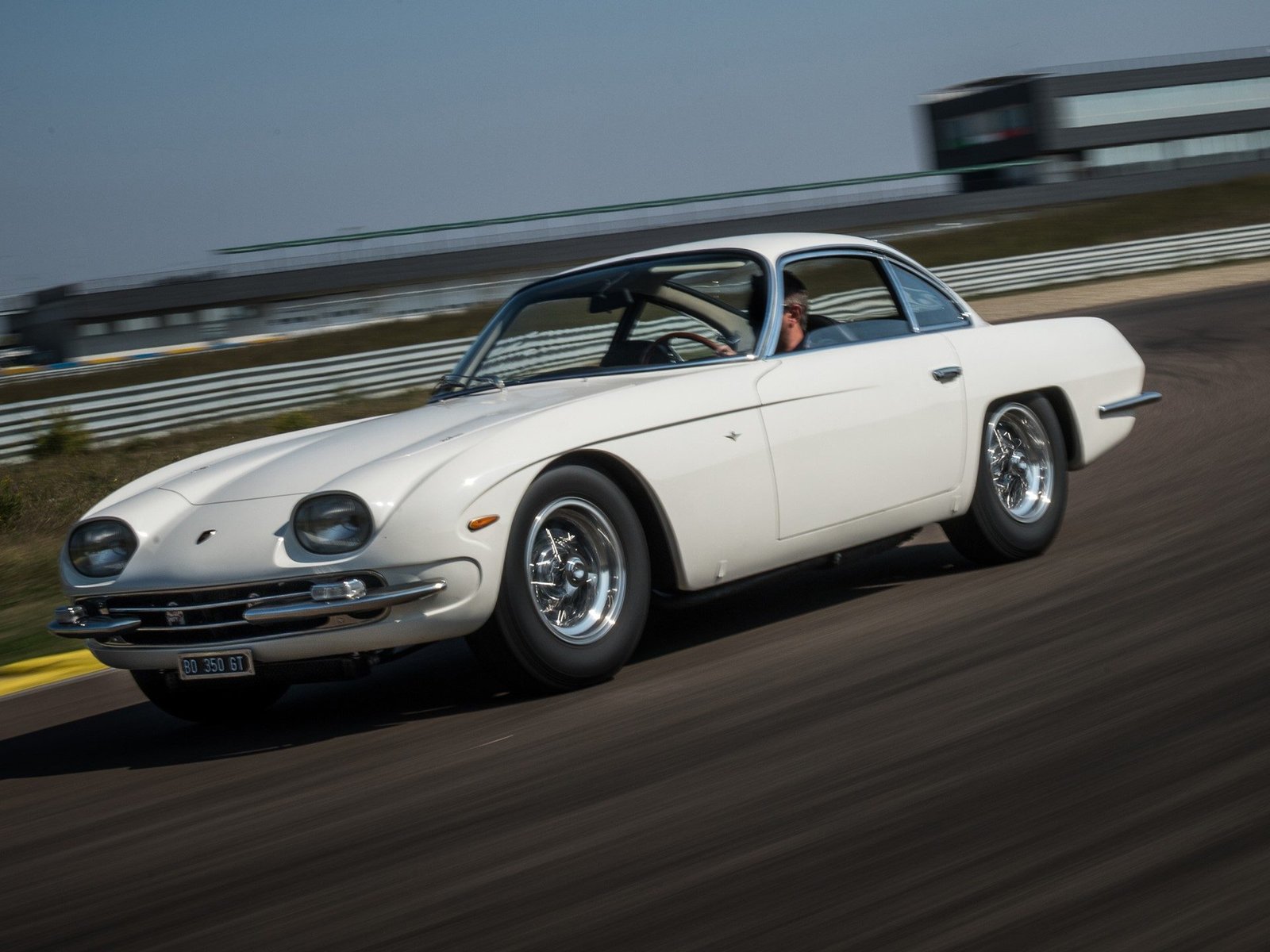 Restored white Lamborghini 350 GT in motion showing chrome trim, wire wheels, and elegant GT proportions