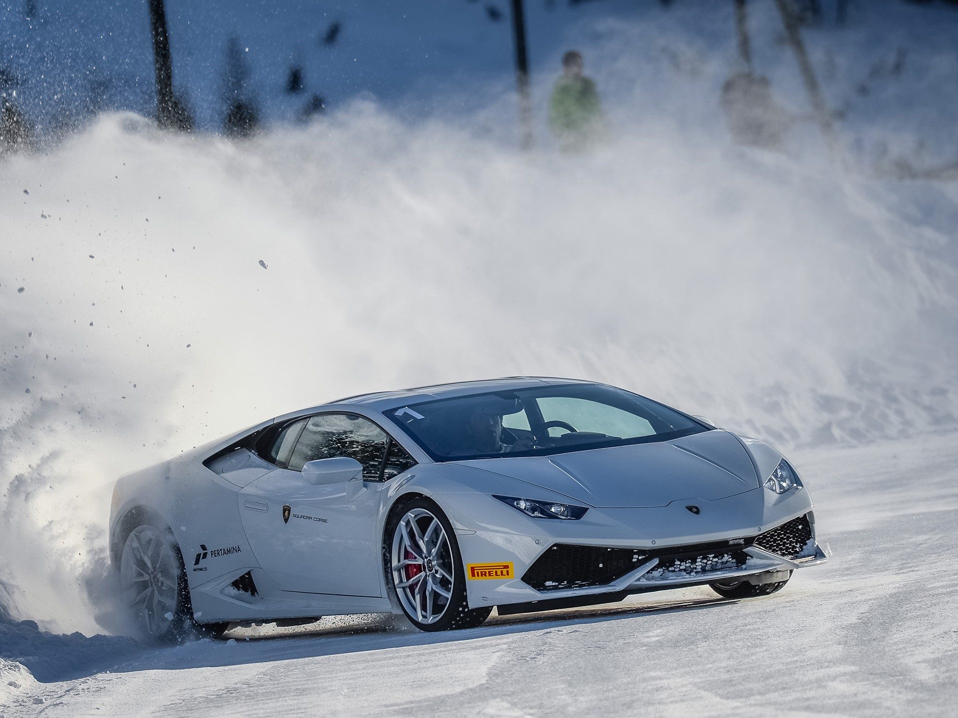 White Lamborghini Huracan drifting through snow during a Winter Accademia event, kicking up a cloud of ice and powder