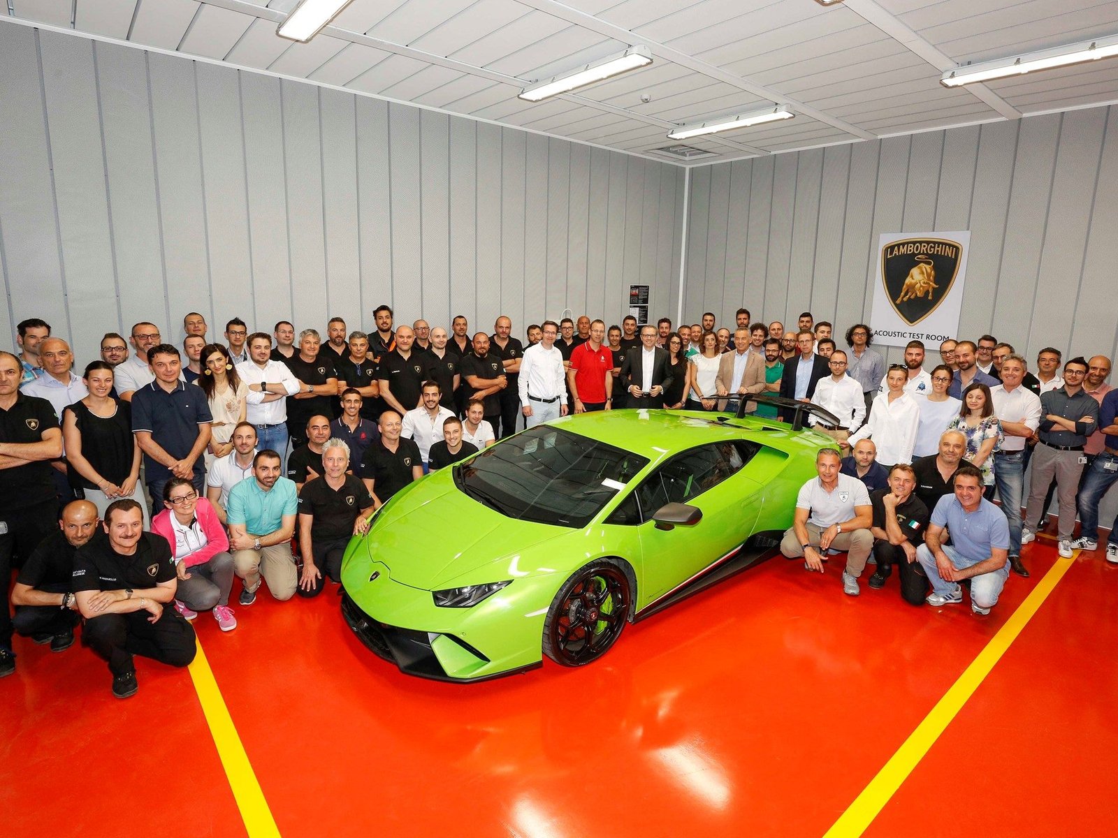 Lamborghini team members pose with a bright green Huracan Performante inside the expanded R&amp;D facility, red floor with yellow stripe visible