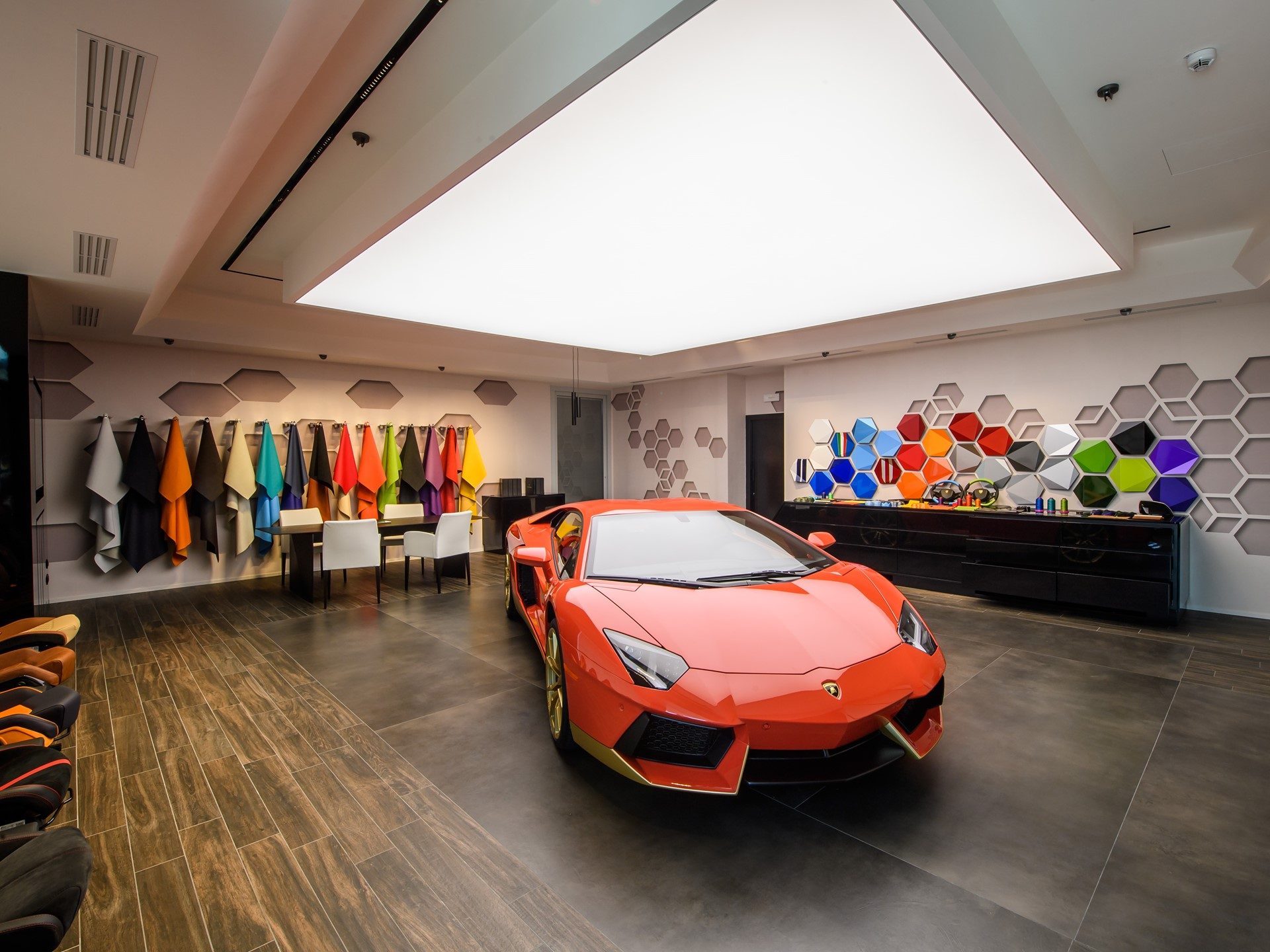 Orange Lamborghini Aventador displayed inside the Ad Personam Studio surrounded by leather swatches and paint samples