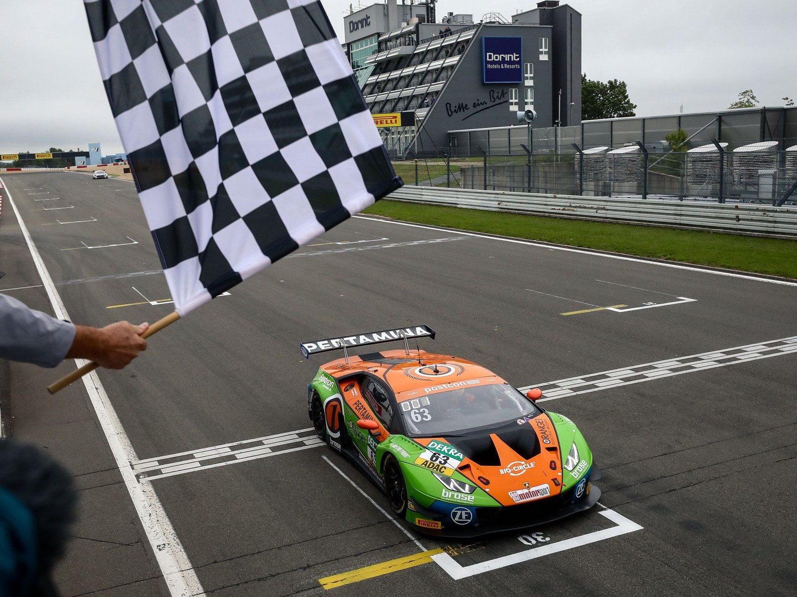 Lamborghini Huracán GT3 number 63 crosses the finish line at the Nürburgring under the checkered flag during the 2019 ADAC GT Masters