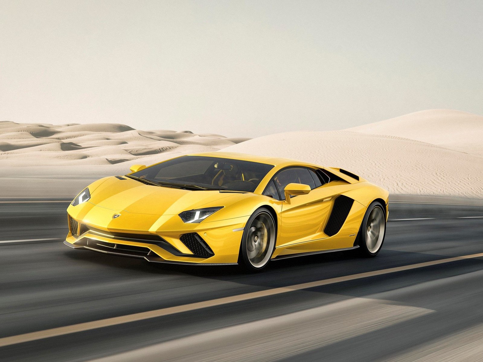 Yellow Lamborghini Aventador S speeding through a desert landscape, showcasing its aggressive front fascia and aerodynamic profile