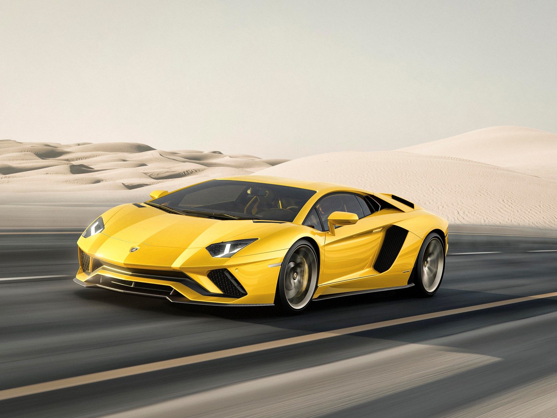 Yellow lamborghini aventador s speeding through a desert landscape, showcasing its aggressive front fascia and aerodynamic profile