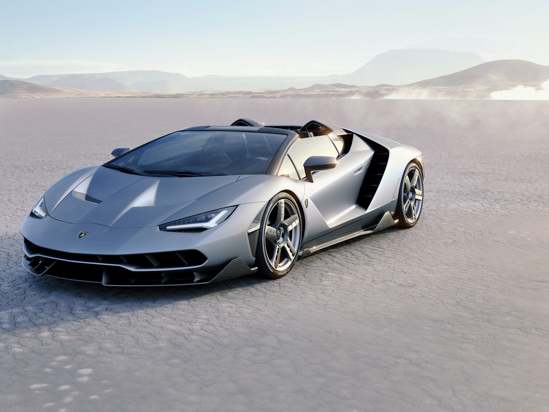 Silver Lamborghini Centenario Roadster showing sharp aerodynamic lines, carbon fiber elements, and prominent air intakes on a desert landscape