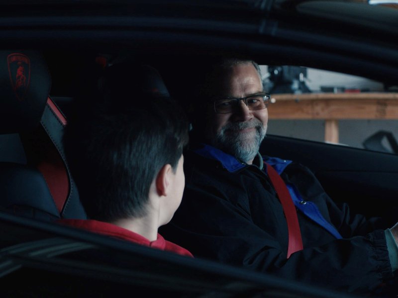 Sterling and Xander Backus seated inside the real Lamborghini Aventador S, with red leather stitching and the Lamborghini crest visible on the seatback