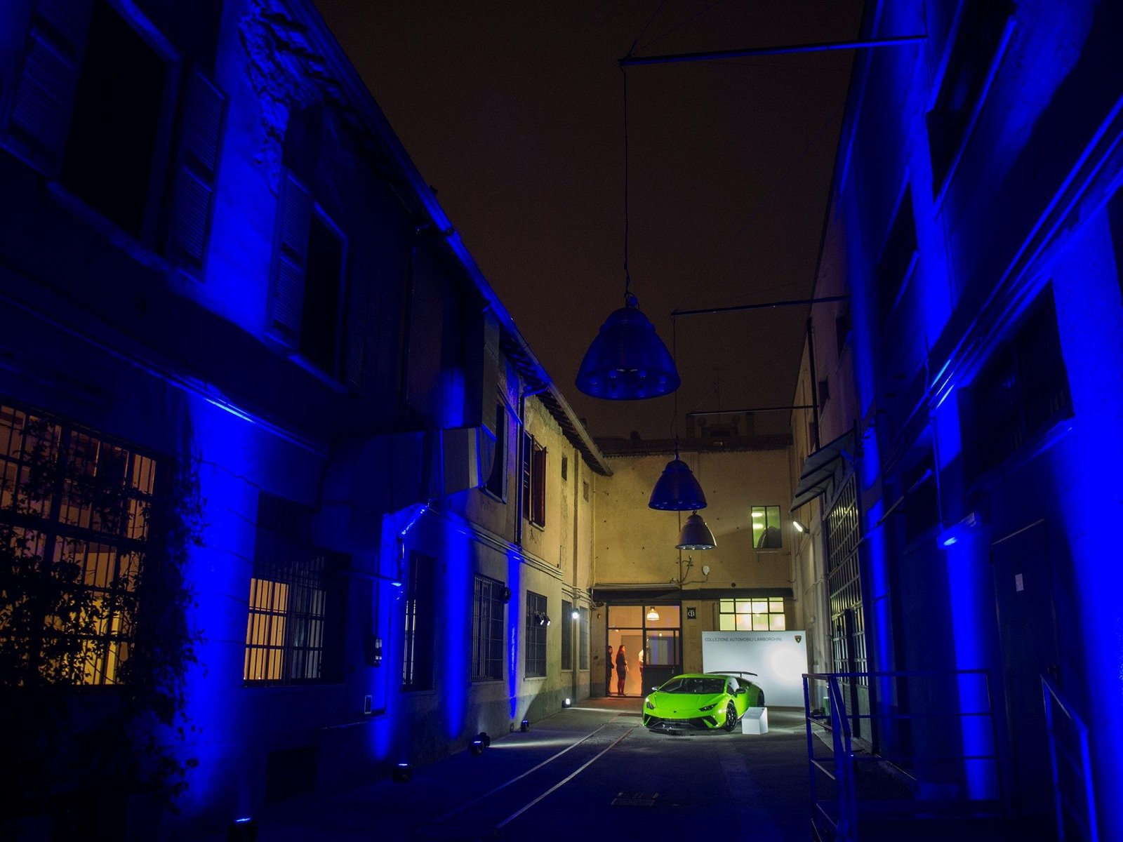 Green Lamborghini Huracán under blue event lighting in a narrow alleyway during Milan Fashion Week