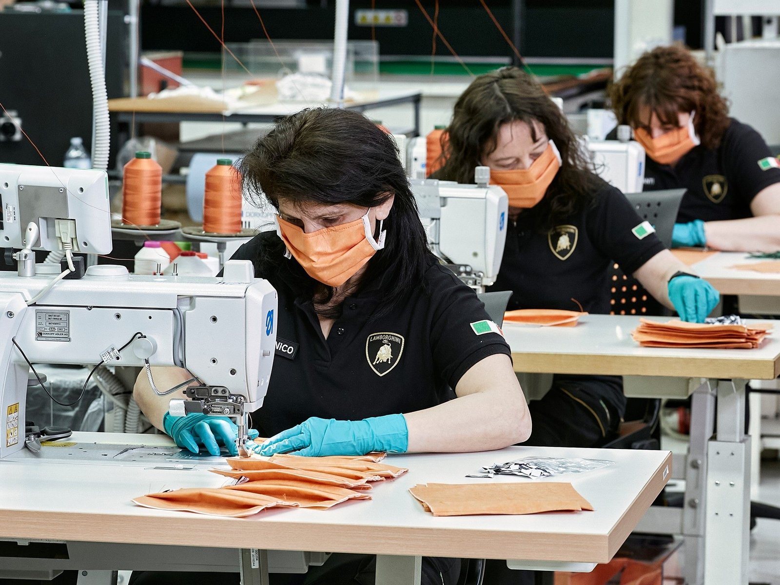 Lamborghini saddlery workers in branded polo shirts producing surgical masks on sewing machines at the Sant'Agata Bolognese factory