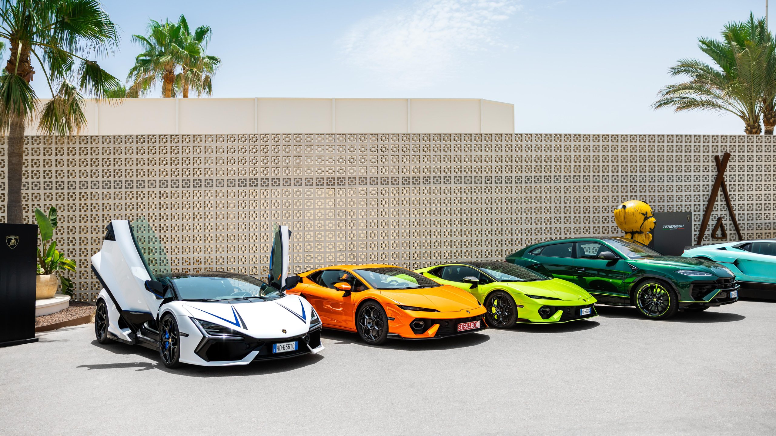 Lamborghini Turns The Mediterranean Into A Showroom With 'Driven By Color' Pop-Ups 9 Vibrant lineup of lamborghini vehicles including a white revuelto, orange huracán tecnica, lime green huracán sterrato, and dark green urus performante at an outdoor event