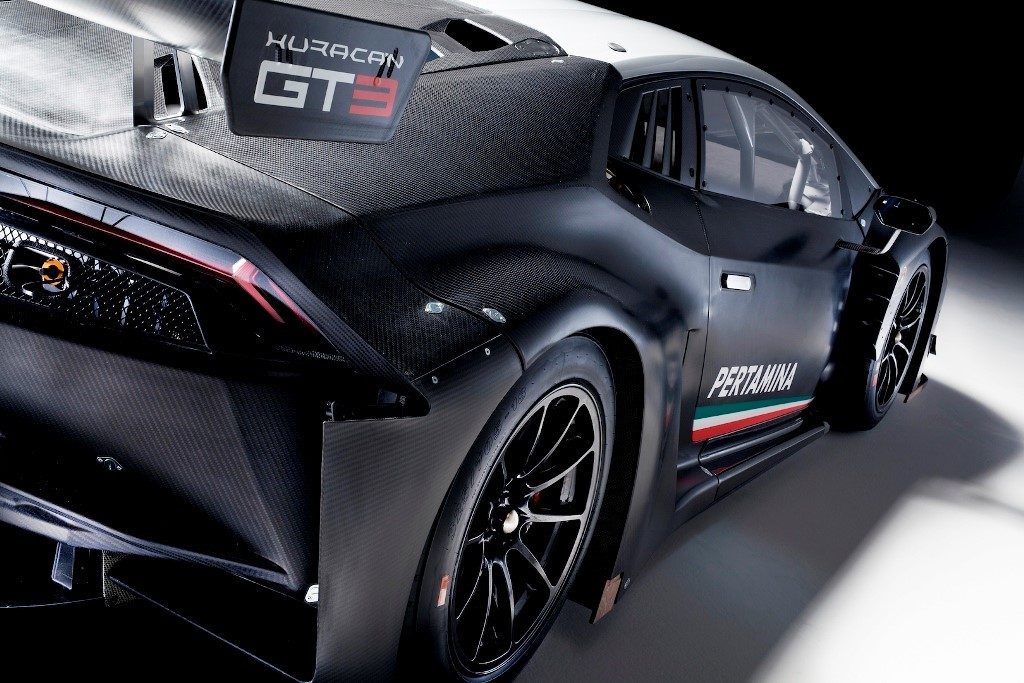 Lamborghini Huracán GT3 race car in black carbon fiber livery, rear three-quarter studio shot showing large rear wing and wide fenders