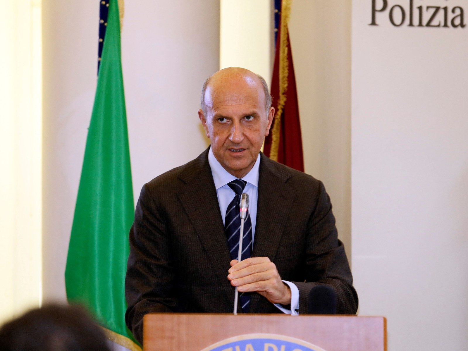 Speaker at podium during the Lamborghini Fiamme Oro sponsorship ceremony in Rome, with flags visible in the background