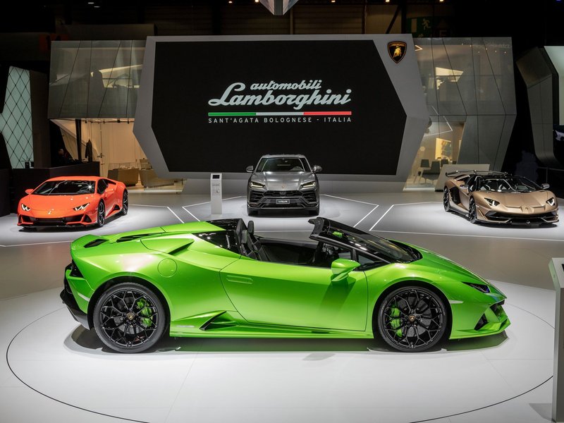 Lamborghini display at the 2019 Geneva Motor Show featuring the Huracán EVO Spyder, Urus, and Aventador SVJ Roadster on a white exhibition floor
