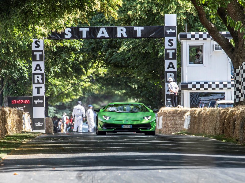 Green Lamborghini Aventador SVJ at the Goodwood hill climb start line with race officials and spectators visible