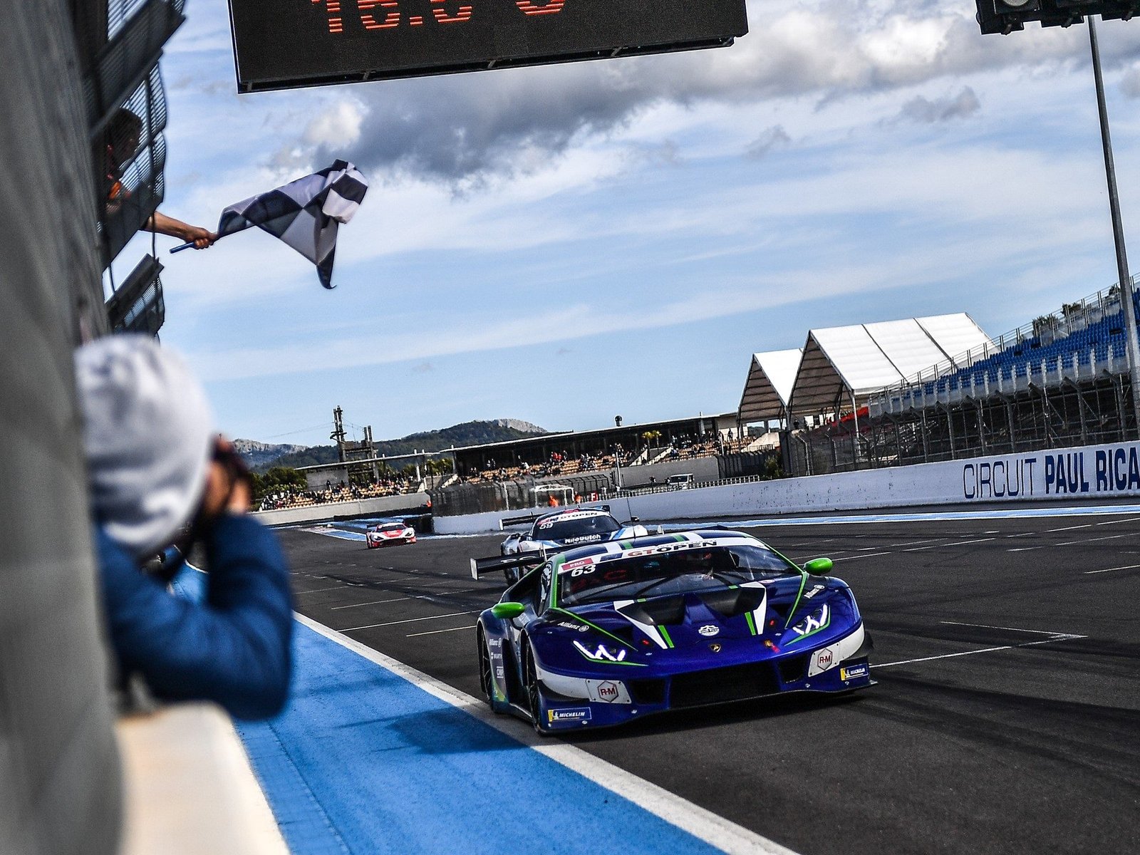 Lamborghini Huracán GT3 Evo number 63 crossing the finish line under the checkered flag at Circuit Paul Ricard