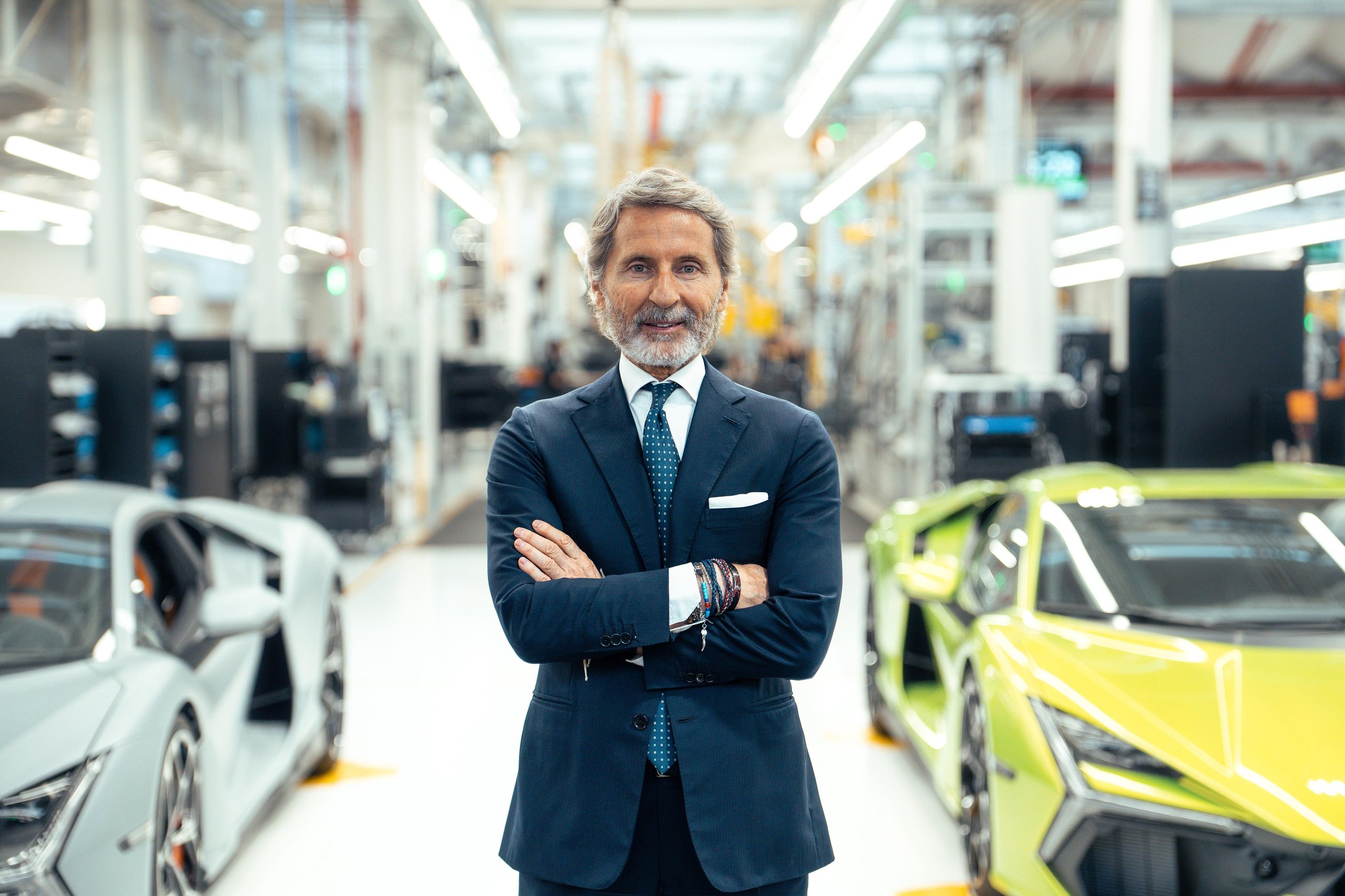 Lamborghini Sold Fewer Cars In H1 2026 And Still Posted Record Revenue. Here'S Why That Matters. 3 Stephan winkelmann standing in the lamborghini factory flanked by a grey and green revuelto