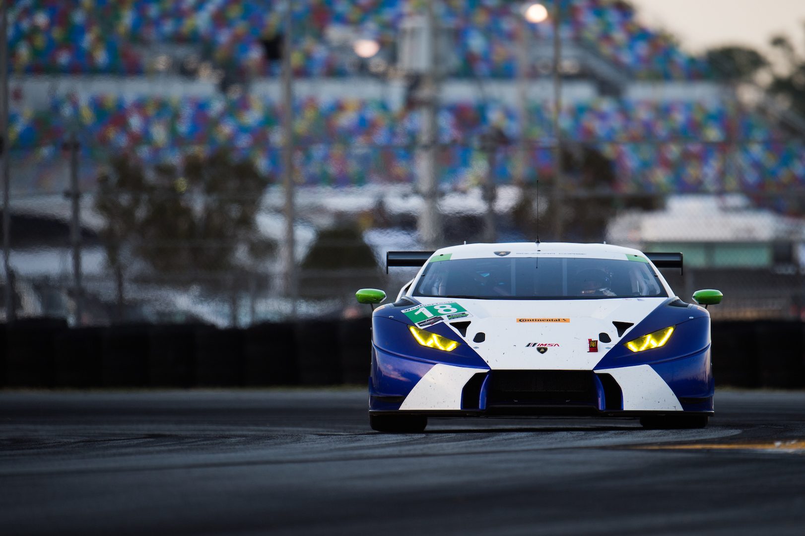 A white and blue Lamborghini Huracán GT3 with green accents racing on the Daytona International Speedway