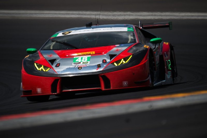 The #48 Paul Miller Racing Lamborghini Huracán GT3 at speed on track, showing its aggressive front splitter, side skirts, and large rear wing in a red, grey, and black livery with green accents