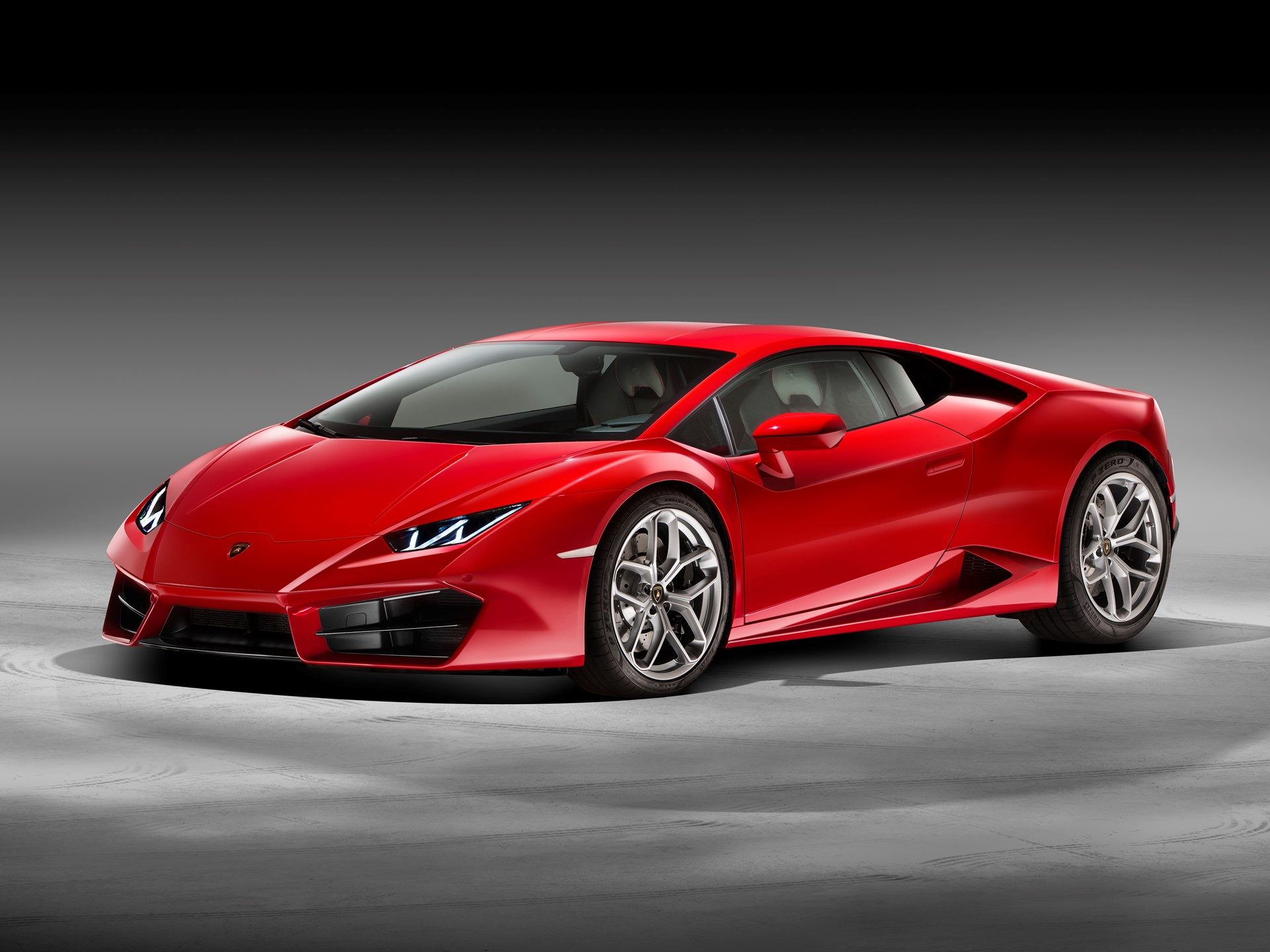 Red Lamborghini Huracán LP 580-2 in studio, showing aggressive front fascia with larger spoiler, LED running lights, and staggered silver multi-spoke wheels