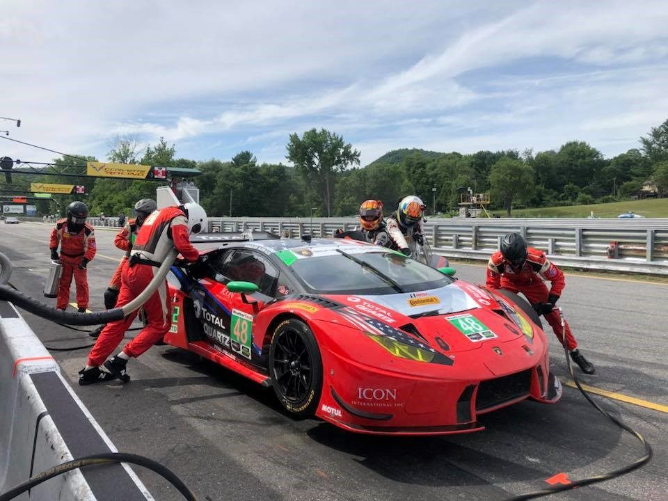 Lamborghini Huracán GT3 pit stop at Lime Rock Park with crew working on the car, large rear wing and racing livery visible