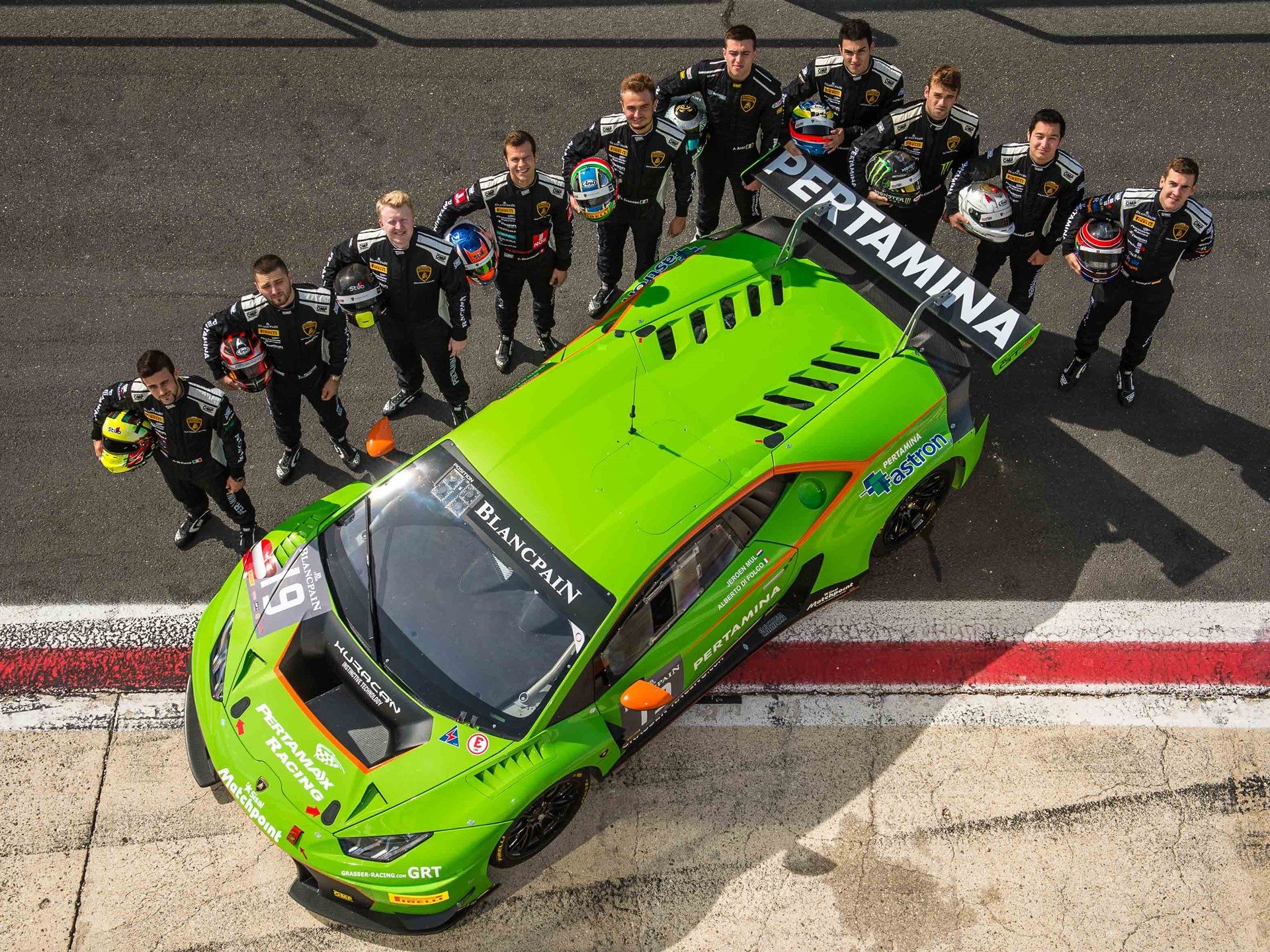 Lamborghini Squadra Corse junior drivers in black racing suits standing around a green Huracán GT3 race car at Vallelunga circuit