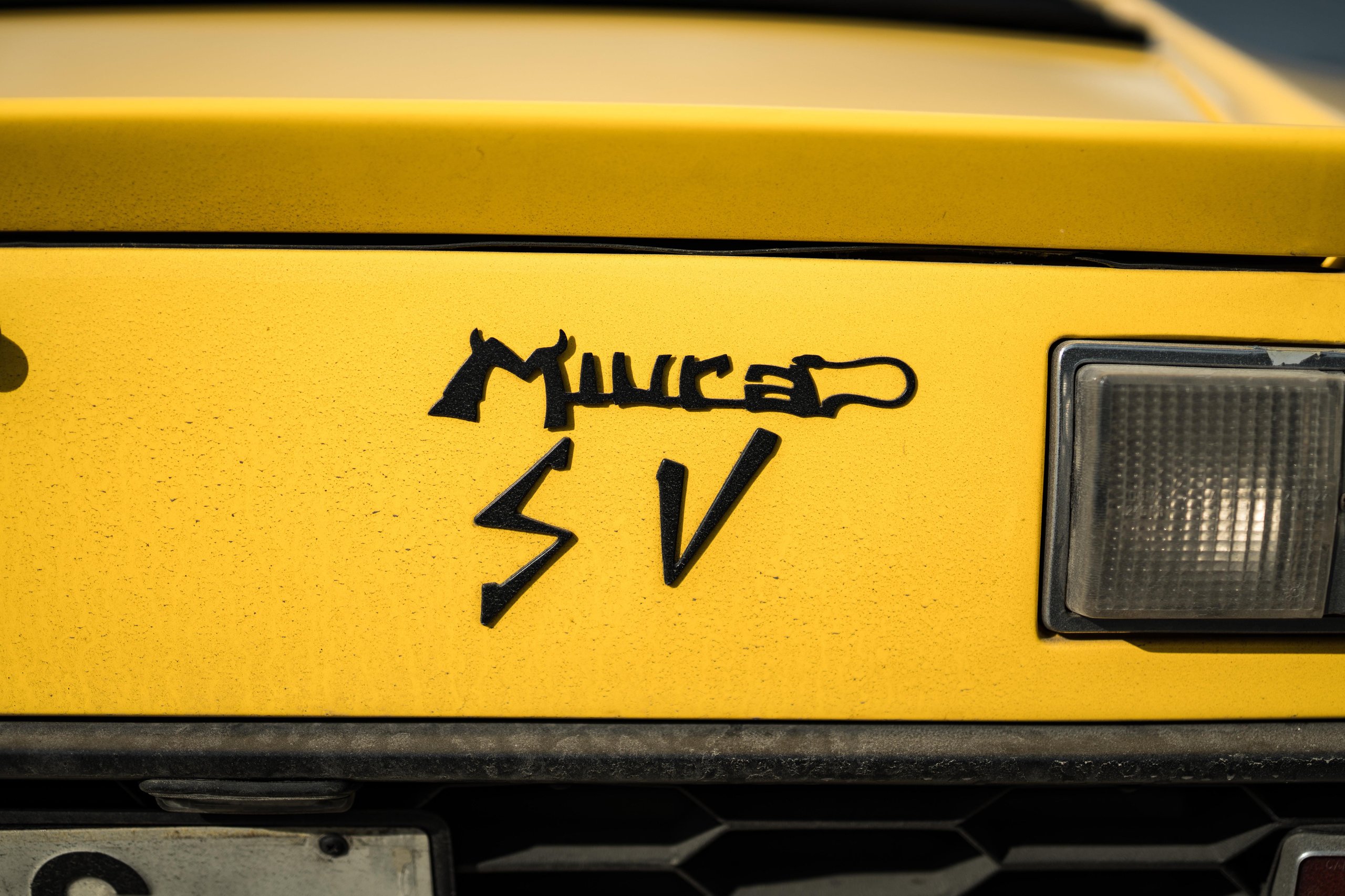 Close-up of the miura sv badge on the rear of a yellow lamborghini miura sv