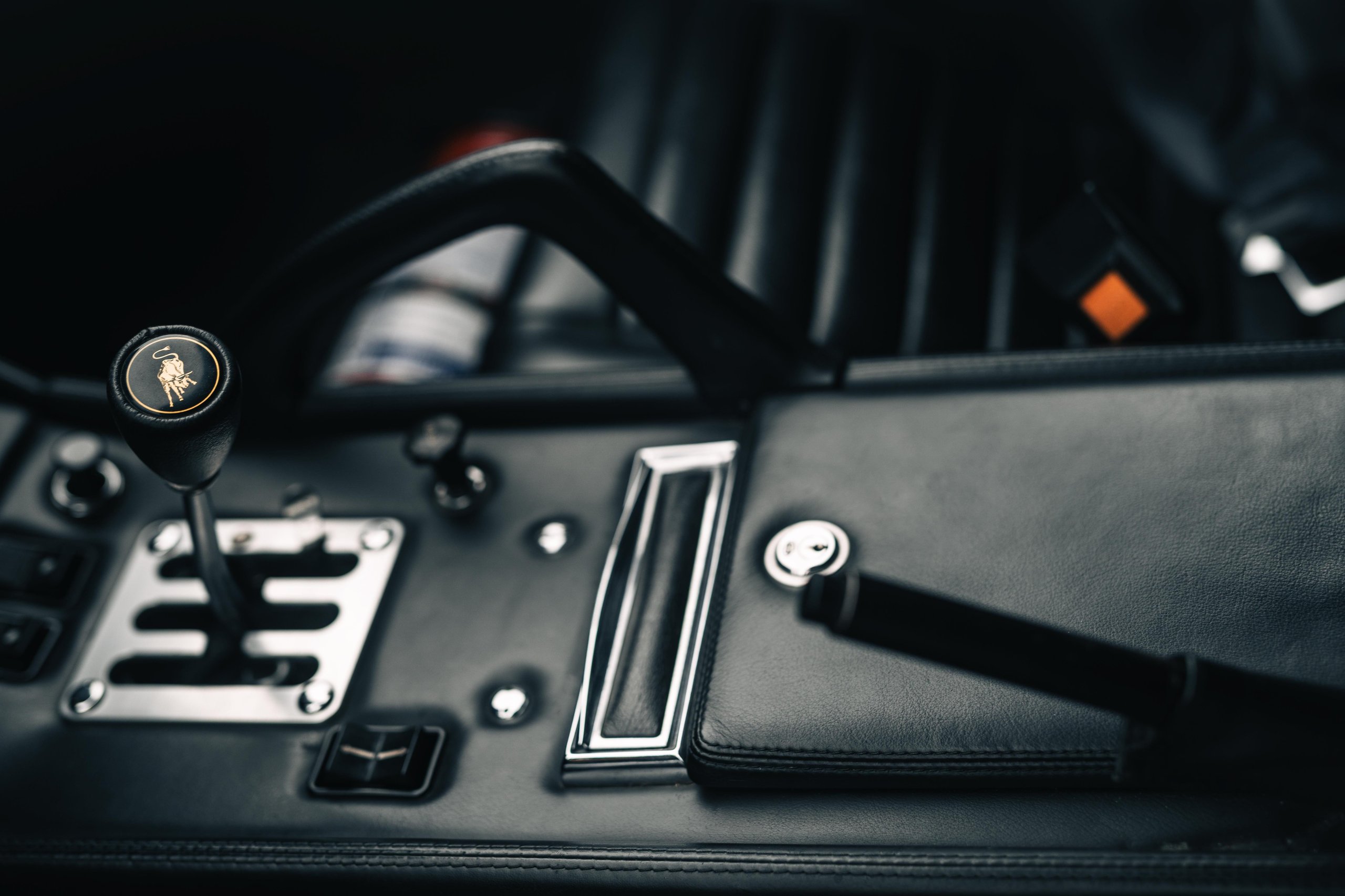 Wide-angle interior shot of the lamborghini miura sv showing the gated manual shifter with golden bull emblem and leather console