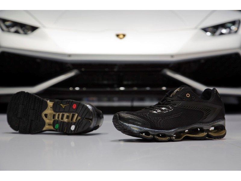 Black and gold Mizuno Wave Tenjin running shoe displayed in front of a white Lamborghini Huracán