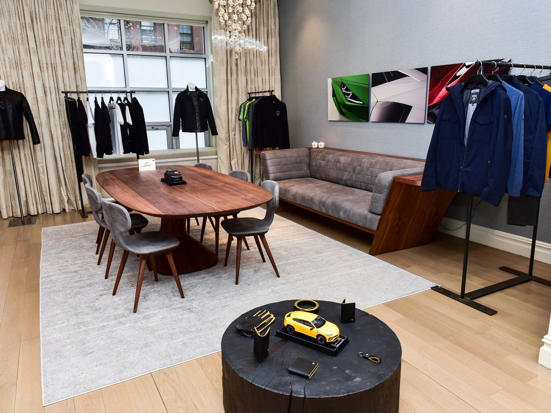 Lamborghini Lounge NYC interior with branded apparel racks, designer wooden table, sofa, and yellow Urus model on display