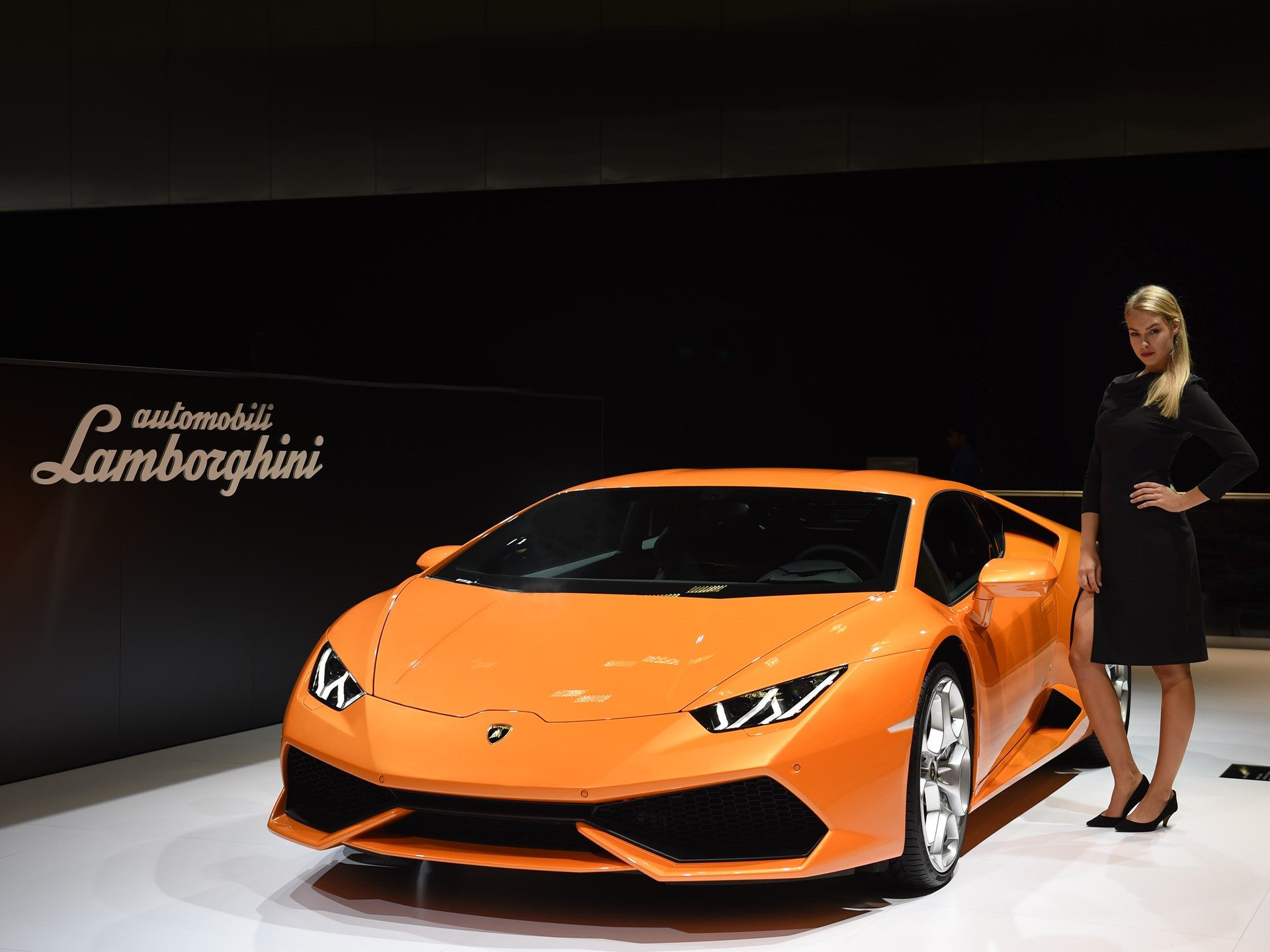 Orange Lamborghini Huracán LP 610-4 displayed under dramatic lighting at an official launch event
