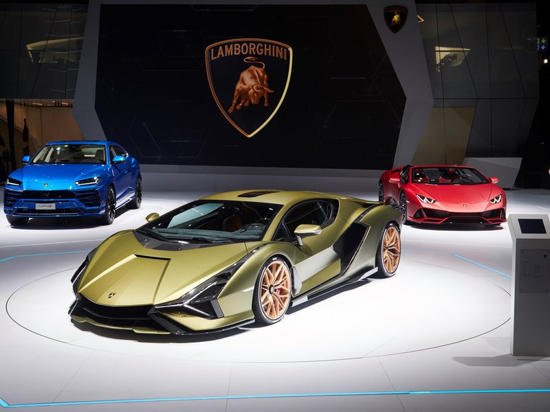 Gold Lamborghini Sián FKP 37 displayed alongside a blue Urus and red Huracán at the IAA 2019 Frankfurt auto show