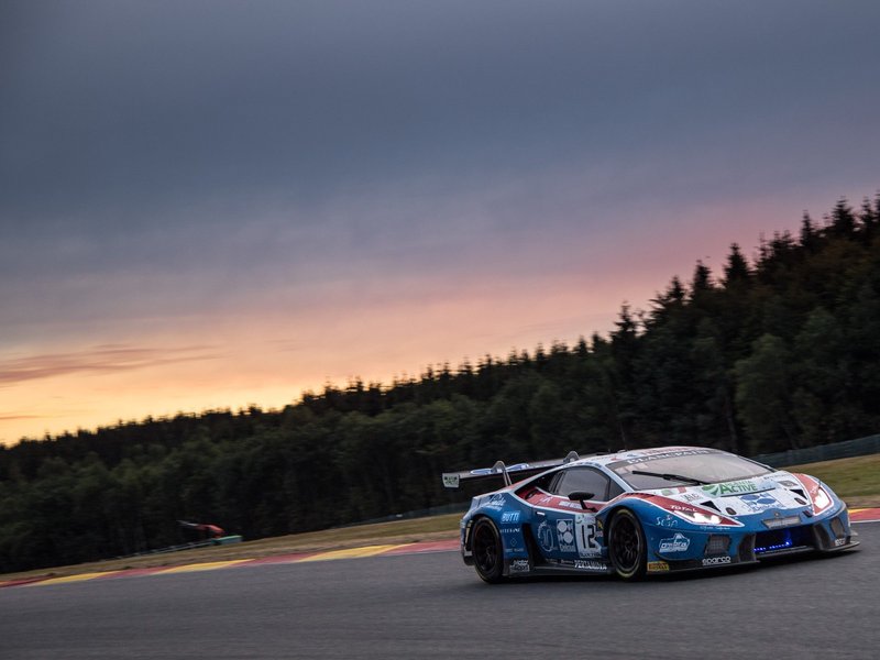Lamborghini Huracán GT3 racing at Spa-Francorchamps during the 2018 24 Hours with a vivid sunset sky behind the circuit