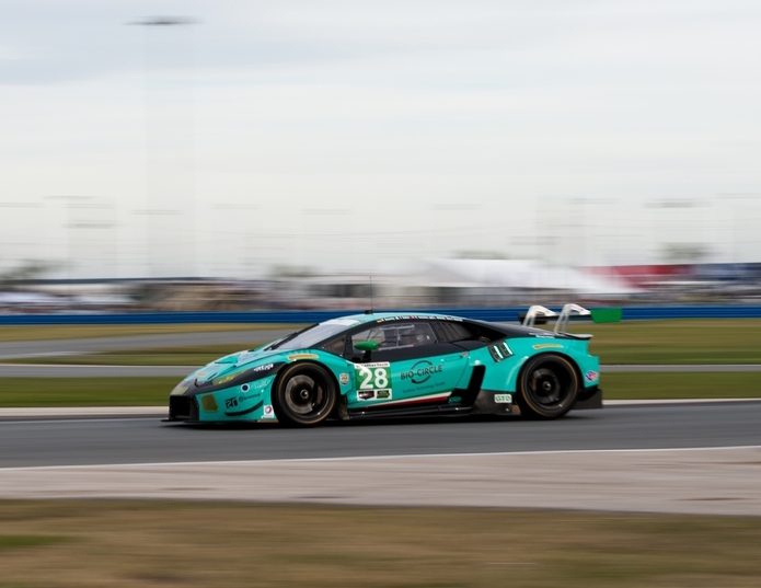 Lamborghini Huracán GT3 number 28 at speed on a racetrack with motion blur, showing its large rear wing and racing livery