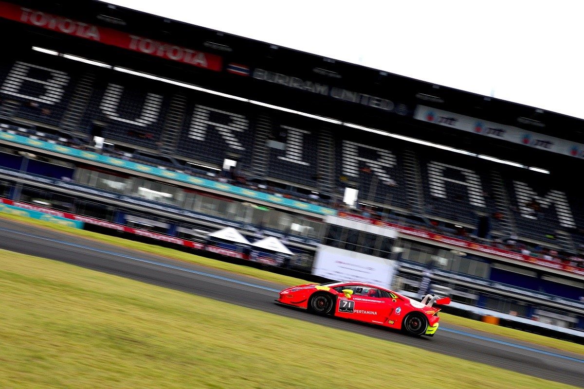 Red Lamborghini Huracán Super Trofeo race car at speed on the Buriram International Circuit with the BURIRAM grandstand visible in the background