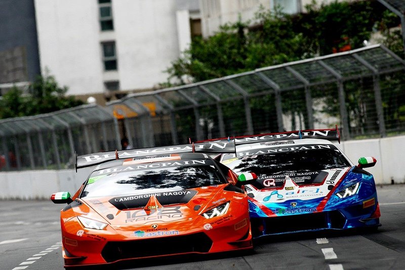 Two Lamborghini Huracán GT3 race cars in close competition on the Kuala Lumpur street circuit, showing aggressive aero elements and large rear wings
