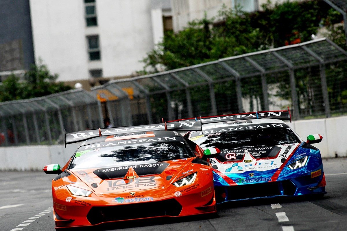 Two Lamborghini Huracán GT3 race cars in close competition on the Kuala Lumpur street circuit, showing aggressive aero elements and large rear wings