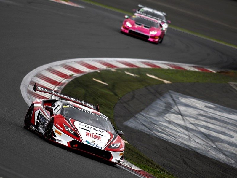 Lamborghini Huracán Super Trofeo race cars battling for position on a racetrack, featuring aerodynamic body kits and large rear wings