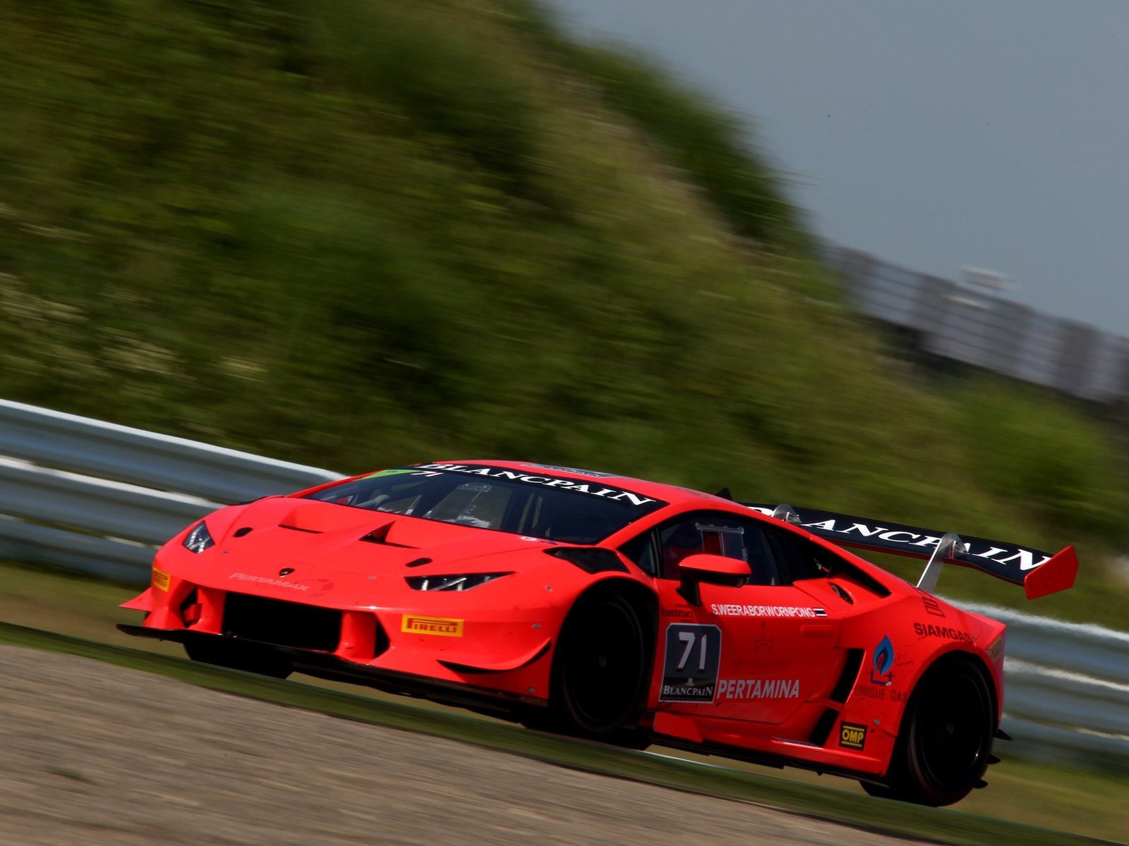Red Lamborghini Huracán Super Trofeo race car at speed on a circuit, showcasing its aerodynamic body kit and large rear wing