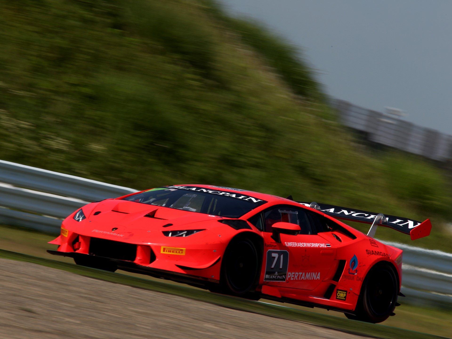 Red Lamborghini Huracán Super Trofeo race car at speed on a circuit, showcasing its aerodynamic body kit and large rear wing