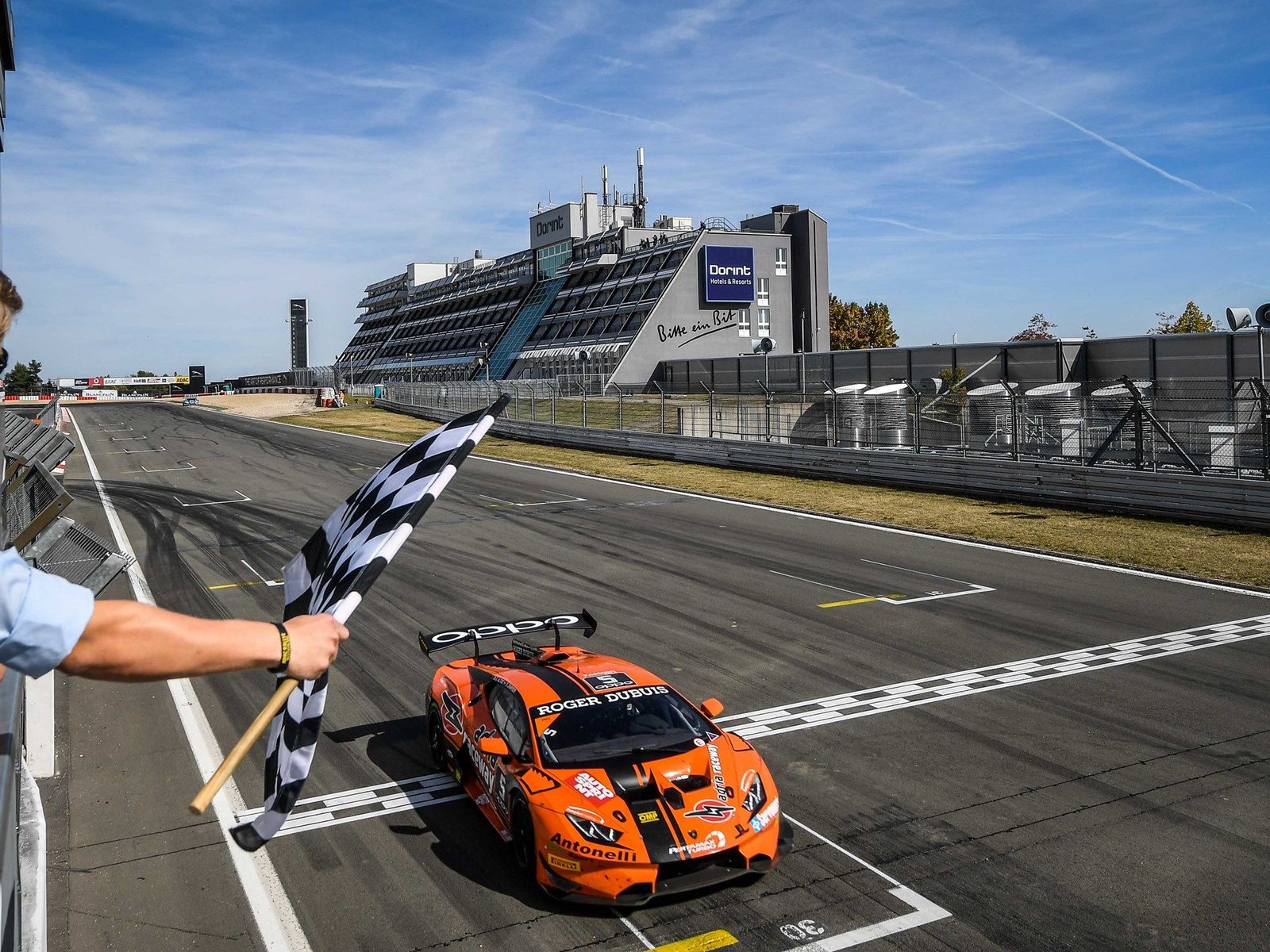Orange Lamborghini Huracán Super Trofeo race car crosses the finish line at Nürburgring under the checkered flag