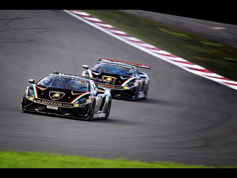 Black Lamborghini Gallardo GT3 race cars with gold and green livery racing at Fuji International Speedway during the 2014 Super Trofeo Asia series