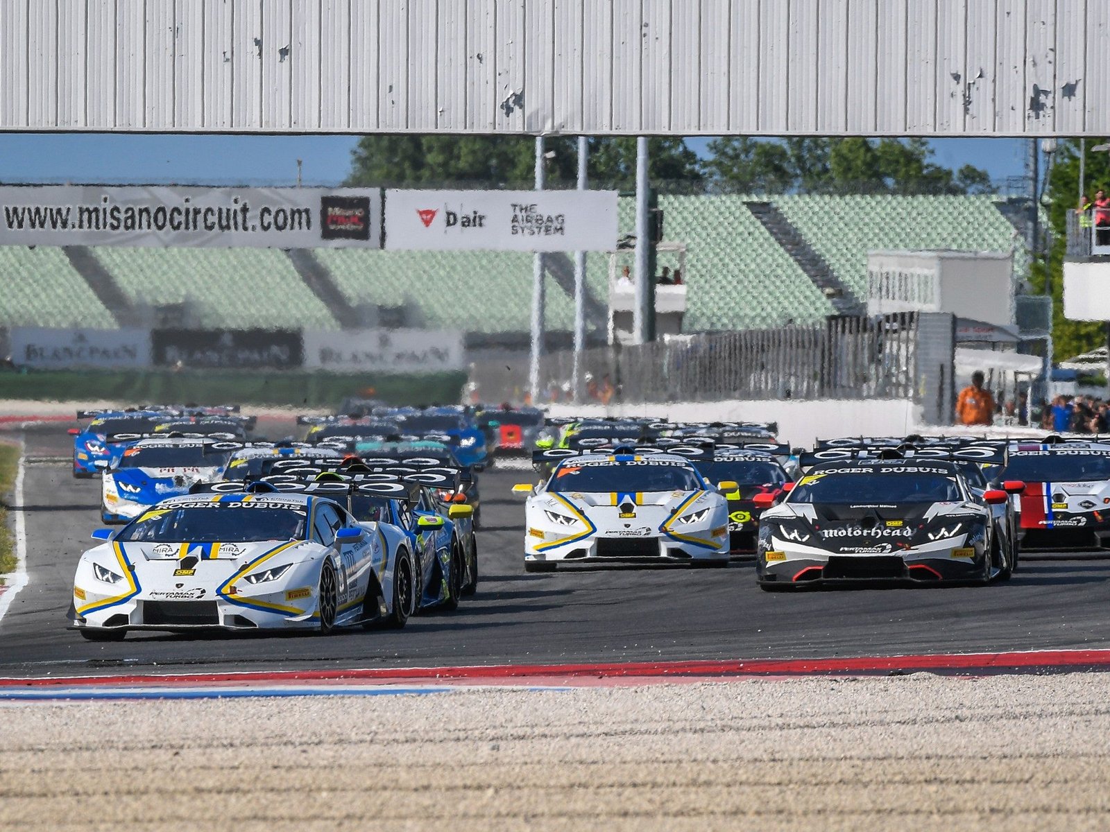 A pack of Lamborghini Huracán Super Trofeo race cars battling for position on track at Misano during the 2018 Super Trofeo Europe round